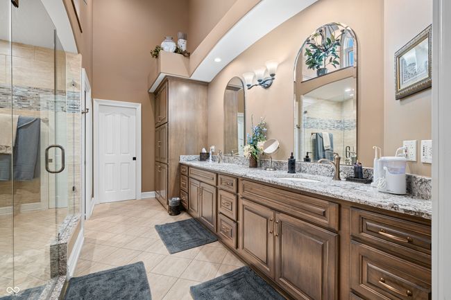 bathroom featuring tile patterned floors, double vanity, a sink, a stall shower, and a high ceiling | Image 47