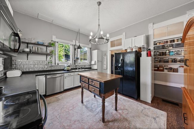 Kitchen with black appliances, dark countertops, light wood-style floors, a textured ceiling, and backsplash | Image 16