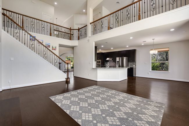 Unfurnished living room featuring dark wood-type flooring, stairway, a towering ceiling, recessed lighting, and arched walkways | Image 19