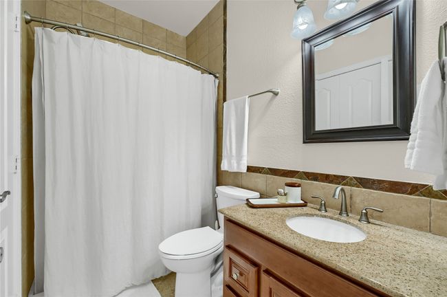 Full bath featuring toilet, vanity, a shower with curtain, and tile walls | Image 24