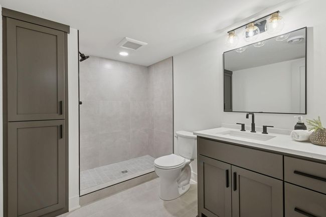 Lower level bath features a custom shower, upgraded tile, faucets & cabinetry. | Image 22