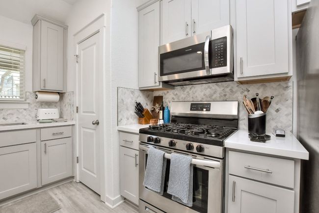 Kitchen with tasteful backsplash, a sink, light countertops, appliances with stainless steel finishes, and light wood-style floors | Image 17