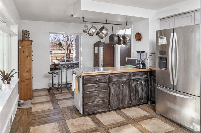 Kitchen with kitchen peninsula, dark brown cabinets, and stainless steel fridge | Image 11