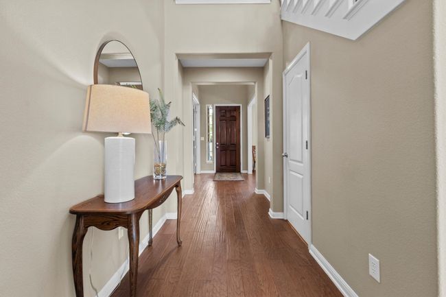 An airy, light-filled living space with dramatic ceilings and a stately stone fireplace creates the perfect backdrop for everyday living. | Image 7