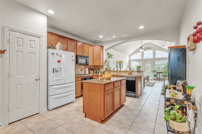 Kitchen featuring black appliances, a peninsula, arched walkways, ceiling fan, and a center island | Image 4