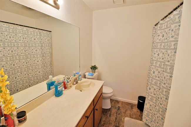 Bathroom featuring toilet, curtained shower, vanity, wood finished floors, and baseboards | Image 11