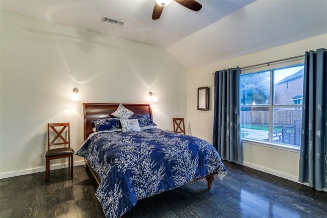 Bedroom featuring wood finished floors, vaulted ceiling, baseboards, multiple windows, and a ceiling fan | Image 13