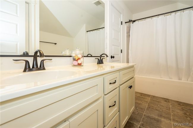 Full bathroom featuring a sink, double vanity, visible vents, and shower / bath combo with shower curtain | Image 28