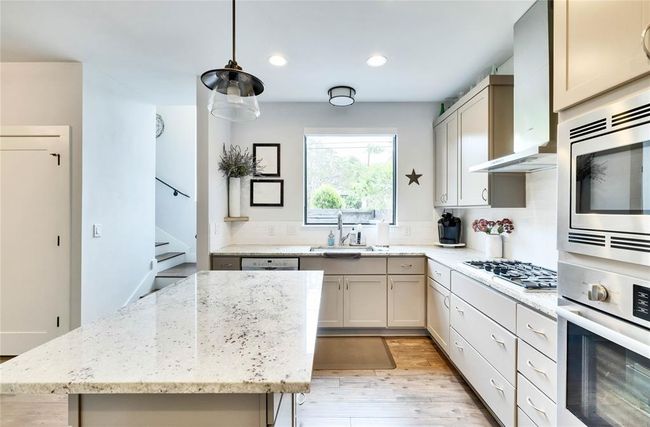 Kitchen featuring stainless steel appliances, light wood finished floors, recessed lighting, light stone countertops, and a center island | Image 8