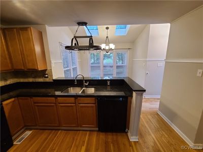 Kitchen featuring dishwasher, light hardwood / wood-style floors, a chandelier, sink, and a skylight | Image 3