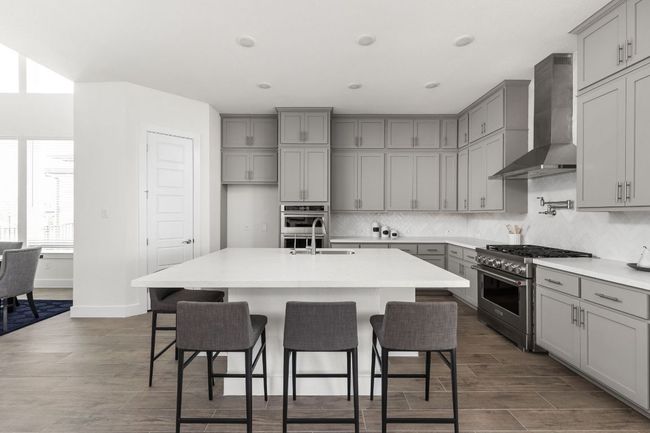 Kitchen featuring gray cabinetry, appliances with stainless steel finishes, wall chimney range hood, a sink, and recessed lighting | Image 15