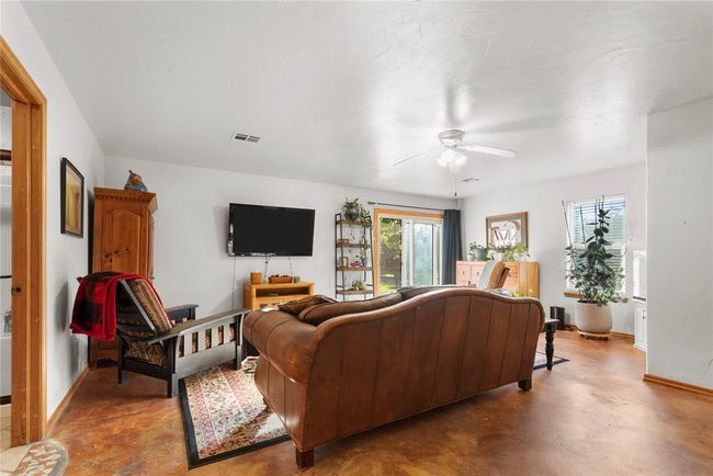 Living room with a healthy amount of sunlight, a ceiling fan, and finished concrete floors | Image 22