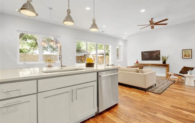 Kitchen with pendant lighting, dishwasher, a sink, light countertops, and light wood finished floors | Image 8