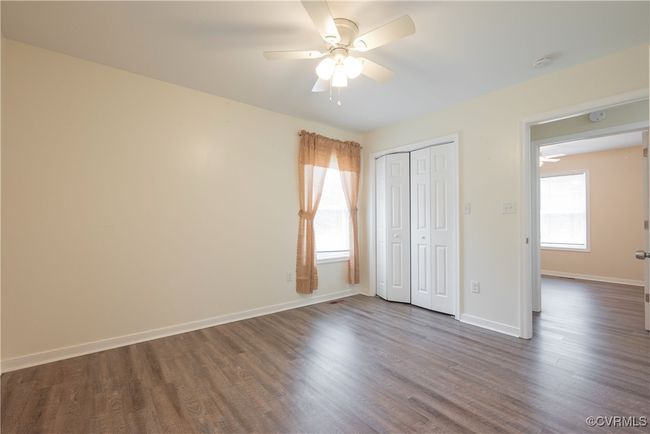 Unfurnished bedroom with a closet, dark wood-style floors, multiple windows, and baseboards | Image 26