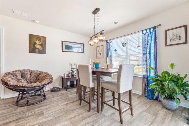 Kitchen with stainless steel appliances, light countertops, a kitchen breakfast bar, wood finished floors, and white cabinets | Image 16