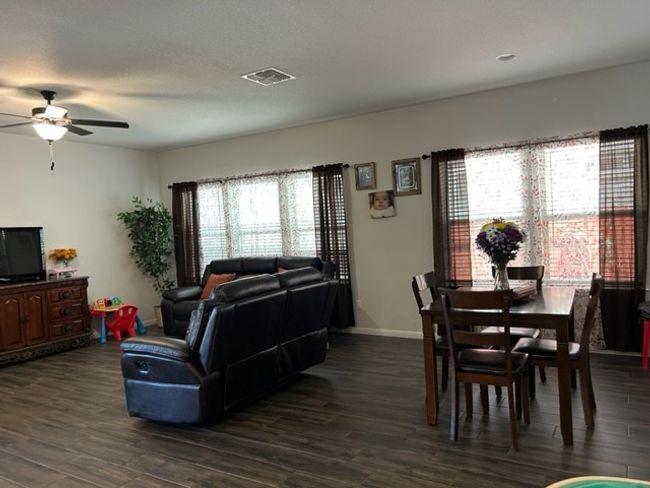 Living room featuring visible vents, dark wood-type flooring, baseboards, and ceiling fan | Image 15