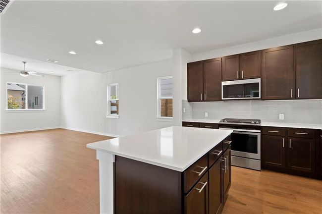 Kitchen with stainless steel appliances, light countertops, light wood-style flooring, decorative backsplash, and healthy amount of natural light | Image 11