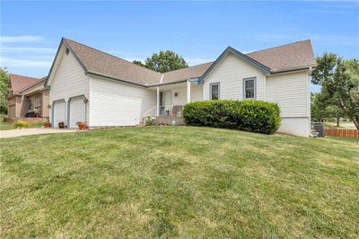 Ranch-style house with a garage, a front yard, and central air condition unit | Image 1