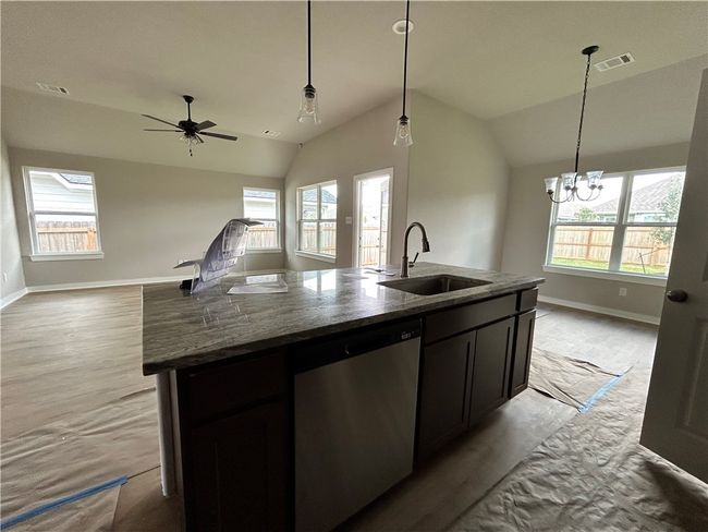 View of kitchen island with granite countertop, dishwasher, and living/dining area | Image 4