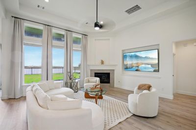 This is a spacious and well-lit living room with large windows offering natural light and outdoor views. It features a cozy fireplace, elegant hardwood flooring, and a modern, neutral color palette, ideal for relaxation or entertaining. | Image 3