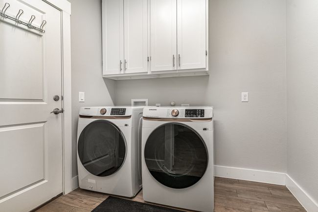 Laundry room featuring cabinet space, wood finished floors, washer and clothes dryer, and baseboards | Image 24