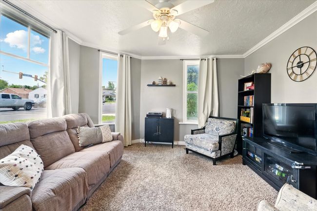 Living room with a ceiling fan, carpet flooring, a textured ceiling, healthy amount of natural light, and crown molding | Image 4