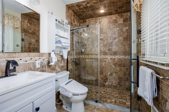 Full bath with vanity, tile walls, toilet, and a shower stall | Image 23