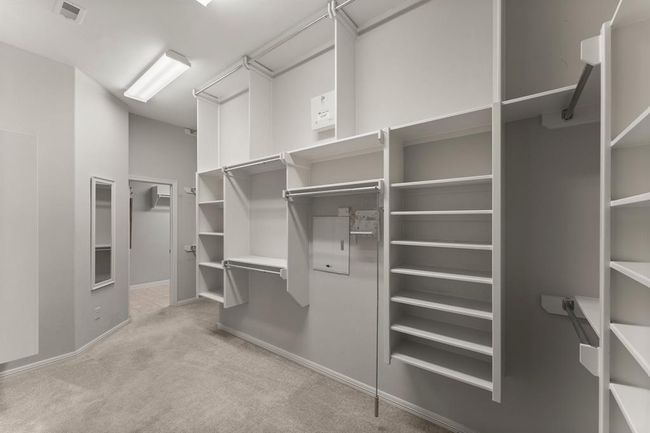 Primary walk-in closet with built-in shelving, double hanging rods, and ample storage space for functionality and organization. Conveniently connects directly to the laundry room for added ease | Image 29