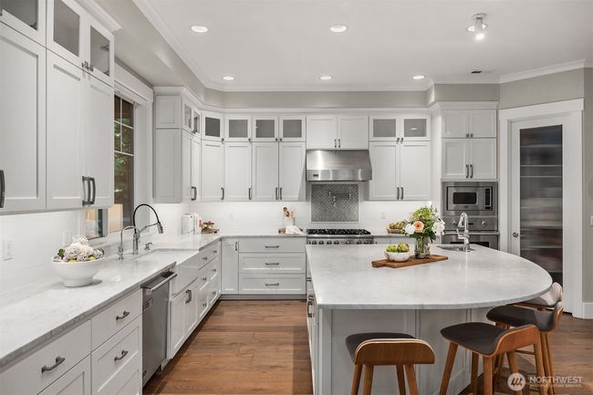 A chef's kiss to this kitchen with marble countertops, Viking Appliances, bosch dishwasher, Sub Zero Fridge, and a walk in pantry. | Image 10