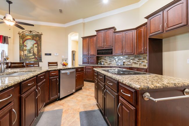 Kitchen with stainless steel dishwasher, black electric cooktop, a ceiling fan, arched walkways, and ornamental molding | Image 8