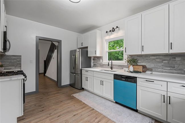 Prepare meals with ease in the brand-new white kitchen, outfitted with durable stone countertops and brand-new appliances throughout. | Image 10