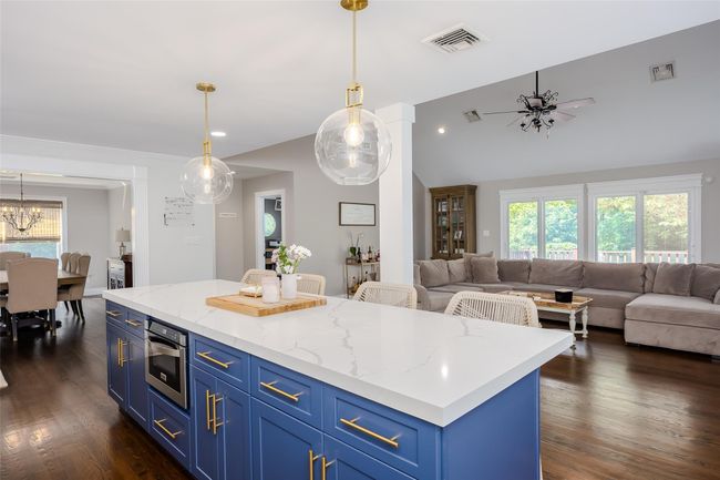 Kitchen with blue cabinets, open floor plan, dark wood-type flooring, vaulted ceiling, and recessed lighting | Image 8