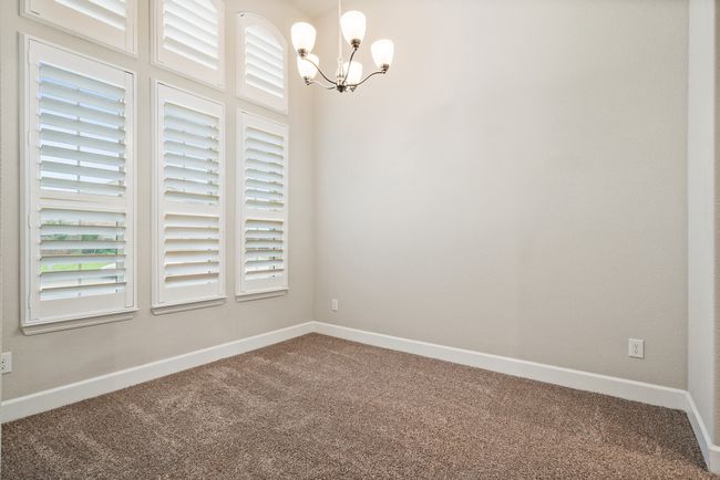 Carpeted spare room with a chandelier and baseboards | Image 5