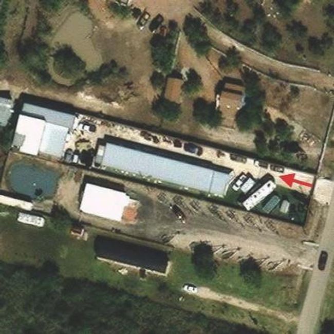 This aerial photo shows the long, narrow property with several buildings, a paved area. The layout is a mix of residential and utility spaces. | Image 4