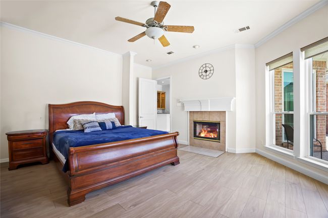 Bedroom featuring ornamental molding, wood finished floors, a tiled fireplace, and multiple windows | Image 15