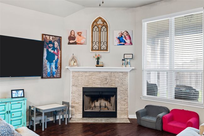 Living room featuring wood finished floors, lofted ceiling, and a fireplace with flush hearth | Image 15