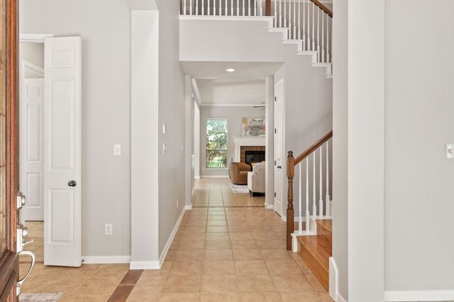 Entrance foyer with stairway, light tile patterned floors, a fireplace, ornamental molding, and a towering ceiling | Image 5