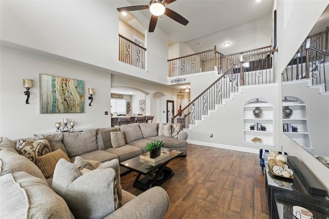 Living area with baseboards, a ceiling fan, stairs, arched walkways, and wood finished floors | Image 8