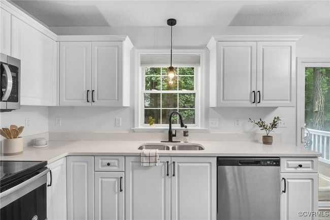 Kitchen with appliances with stainless steel finishes, a sink, white cabinetry, and light countertops | Image 7