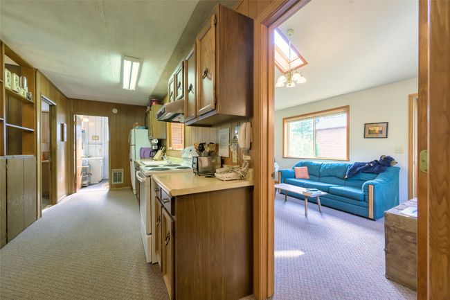 Kitchen with light carpet, white electric range oven, brown cabinets, light countertops, and wooden walls | Image 25