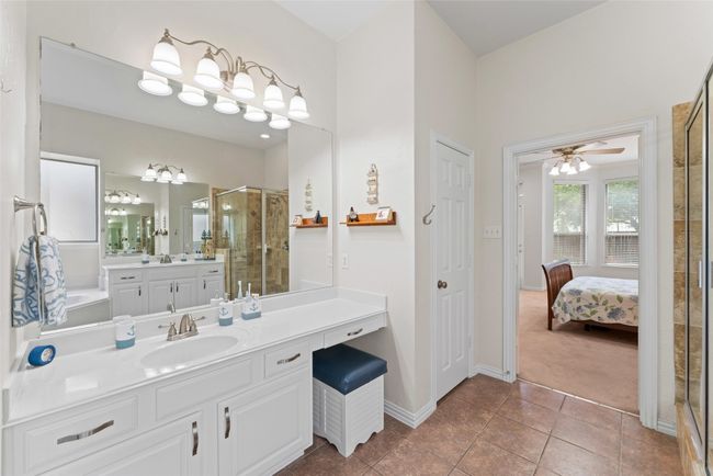 Full bathroom featuring a stall shower, vanity, ensuite bathroom, tile patterned floors, and a ceiling fan | Image 19