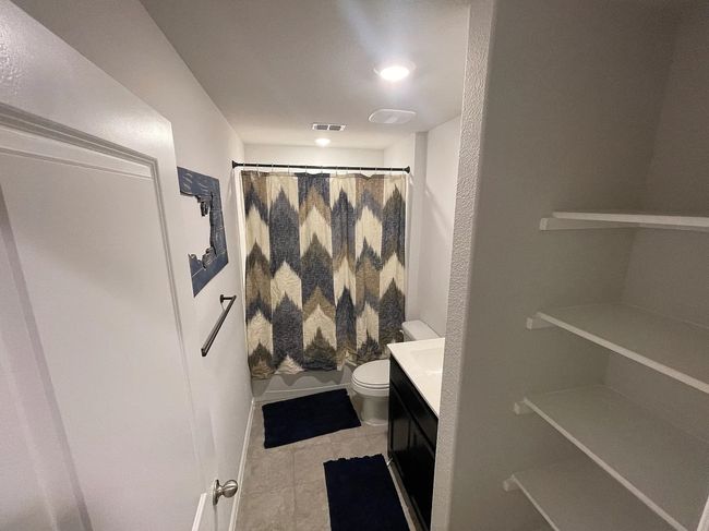 Bathroom featuring tile patterned floors, toilet, visible vents, a shower with shower curtain, and vanity | Image 10