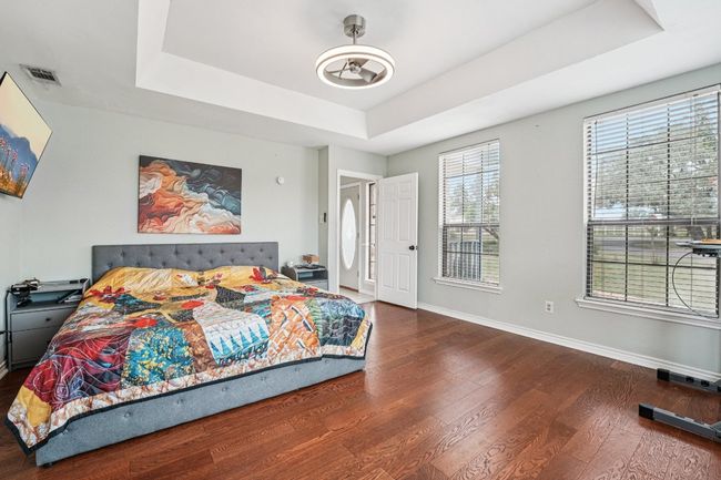 Bedroom featuring a raised ceiling and wood finished floors | Image 15