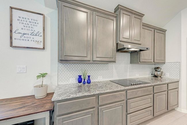Decorative tile backsplash, smooth surface 5-burner cooktop and vented exhaust fan overhead also highlight the kitchen. | Image 11