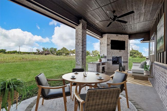 View of patio / terrace with ceiling fan, an outdoor stone fireplace, and outdoor dining area | Image 28