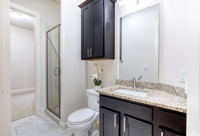 Full bathroom with granite, separate shower, and access from hallway and secondary bedroom. | Image 22