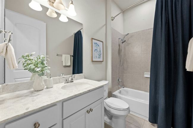 The well-appointed shared guest bathroom features a sleek granite-topped vanity and ample storage. | Image 24