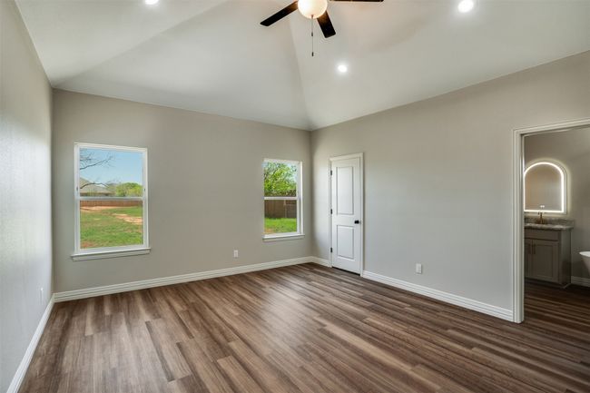Unfurnished bedroom with dark wood-style floors, ensuite bathroom, baseboards, recessed lighting, and high vaulted ceiling | Image 12