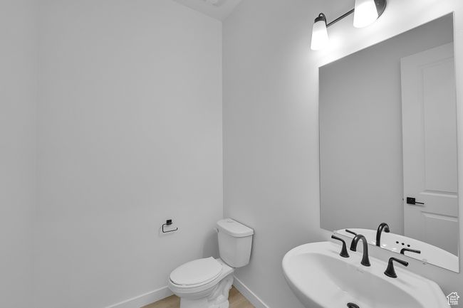 Half bathroom featuring toilet, a sink, baseboards, and wood finished floors | Image 10