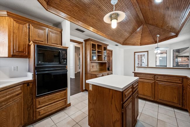 This gourmet kitchen boasts unique features. It is a cook's dream. Custom wood cabinets provide loads of storage. Look at the abundance of workspace. Ceramic tile flooring make cleaning a breeze. I love the ceiling. The craftmanship of the stained wood cathedral ceiling give a hint to the workmanship of the home. | Image 20